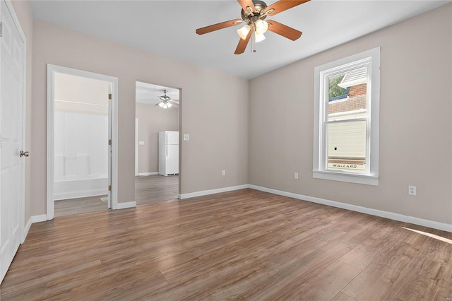 interior space featuring white fridge, wood-type flooring, ceiling fan, and connected bathroom