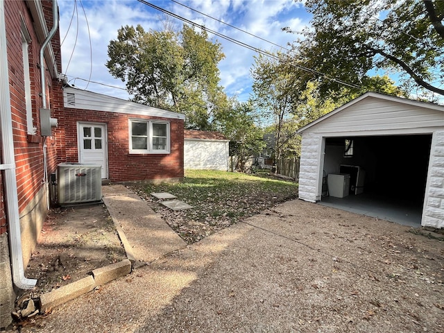 view of yard featuring a garage, an outbuilding, and central AC