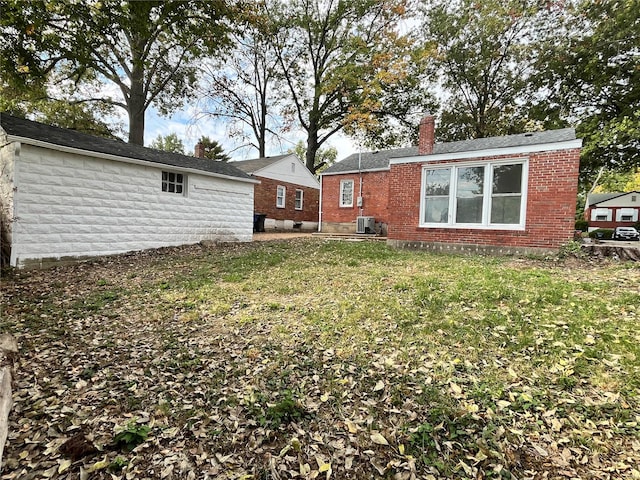 rear view of property featuring central AC unit and a yard