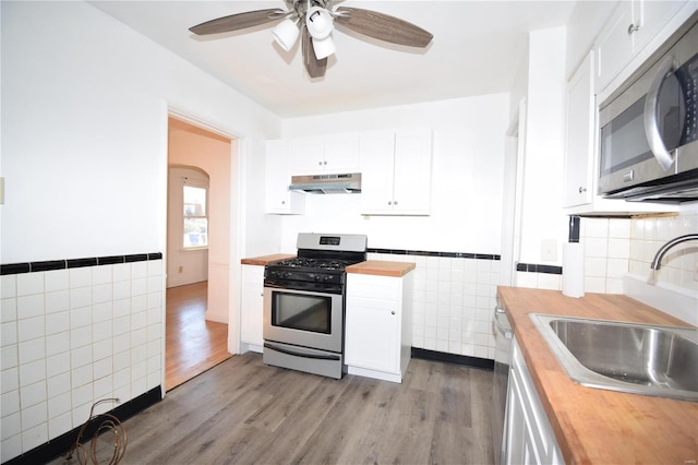 kitchen featuring stainless steel appliances, white cabinetry, extractor fan, sink, and light hardwood / wood-style flooring