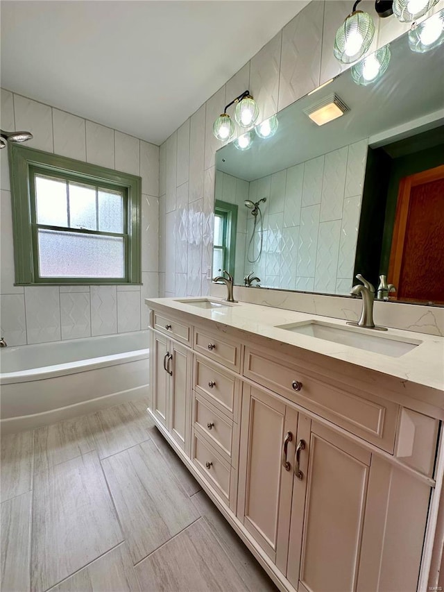 bathroom featuring tile walls, a sink, shower / bathing tub combination, and double vanity