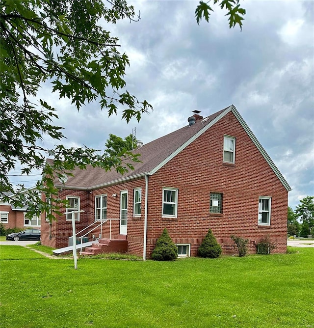 view of front of property featuring cooling unit, a front yard, brick siding, and a chimney