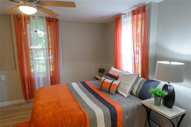 bedroom featuring hardwood / wood-style floors, ceiling fan, and multiple windows