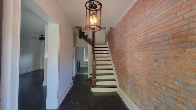 stairway featuring brick wall, ornamental molding, wood-type flooring, and ceiling fan