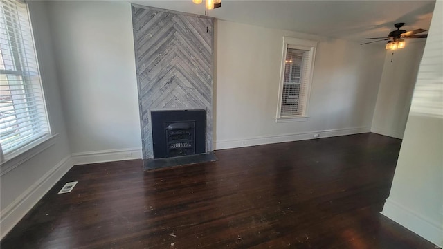 unfurnished living room with dark hardwood / wood-style floors, a large fireplace, and ceiling fan