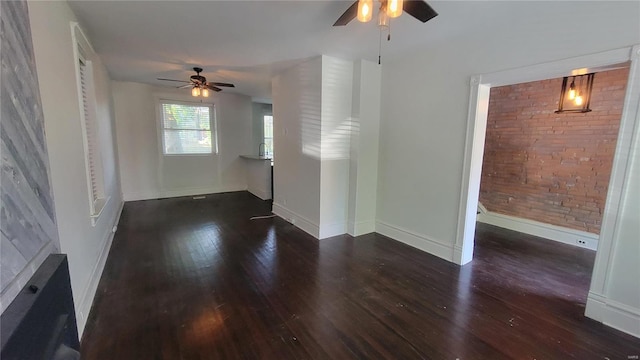 unfurnished living room with ceiling fan, brick wall, and dark hardwood / wood-style flooring