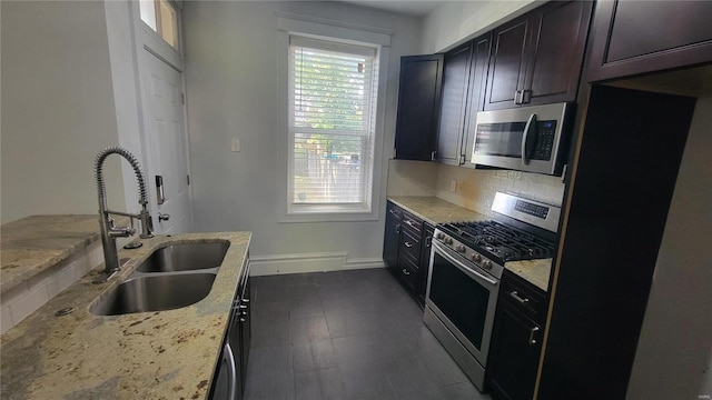 kitchen with decorative backsplash, stainless steel appliances, light stone counters, and sink