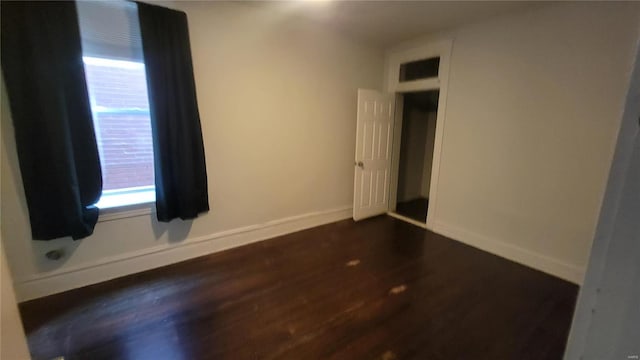 unfurnished room with dark wood-type flooring