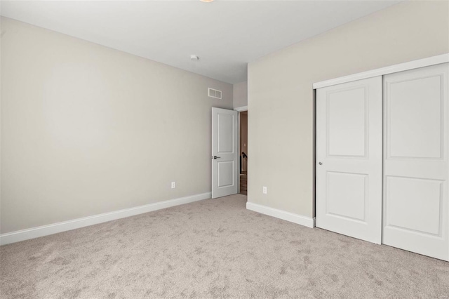 unfurnished bedroom featuring light colored carpet and a closet