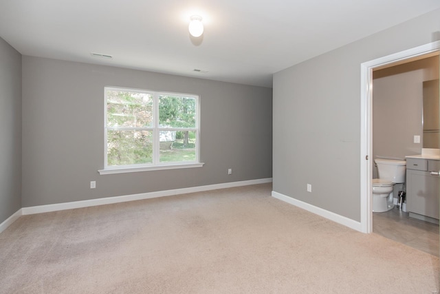 unfurnished bedroom with light colored carpet and ensuite bath