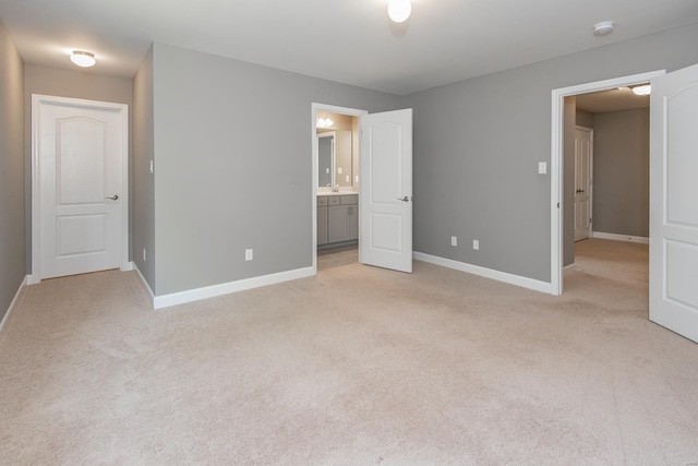 unfurnished bedroom with ensuite bathroom and light colored carpet