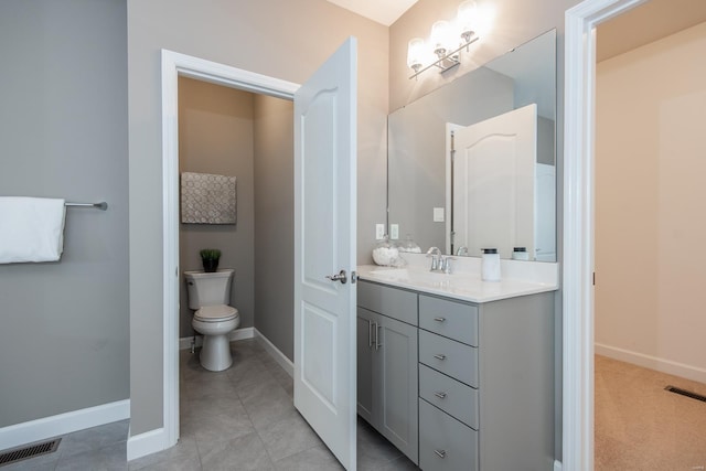 bathroom with toilet, vanity, and tile patterned flooring