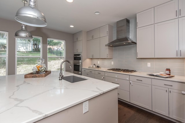 kitchen with wall chimney exhaust hood, hanging light fixtures, stainless steel appliances, light stone countertops, and dark hardwood / wood-style flooring