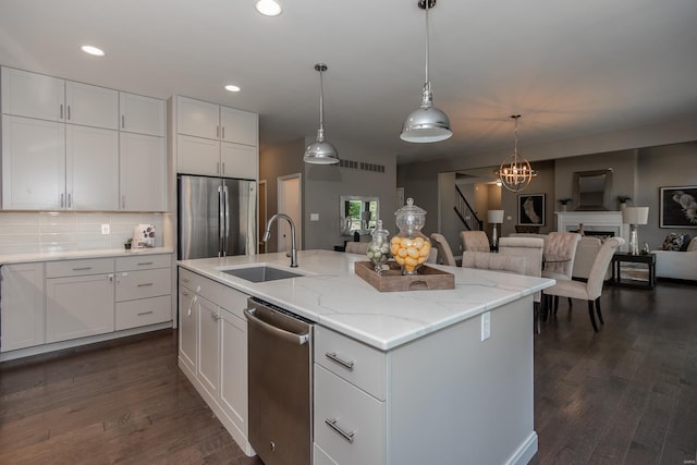 kitchen with sink, appliances with stainless steel finishes, white cabinets, and an island with sink