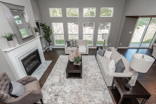 living room featuring a high ceiling, a high end fireplace, plenty of natural light, and dark hardwood / wood-style floors