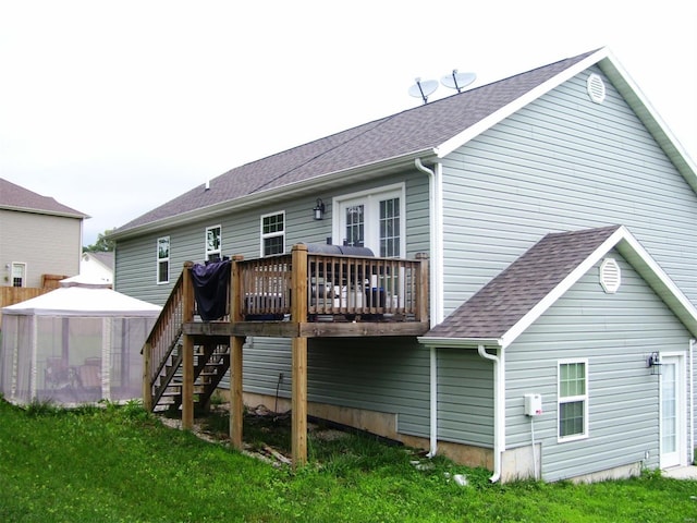 rear view of house featuring a gazebo, a wooden deck, and a lawn