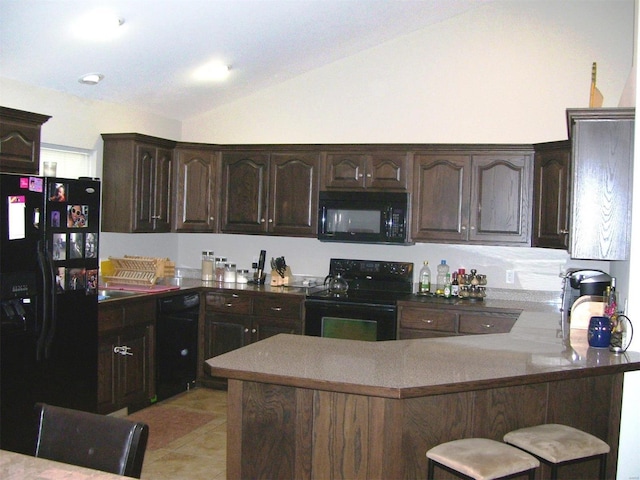 kitchen featuring vaulted ceiling, black appliances, a kitchen breakfast bar, dark brown cabinetry, and kitchen peninsula