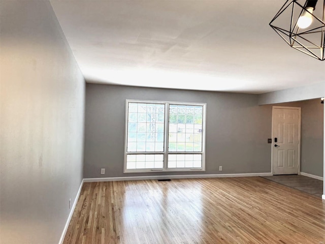 spare room with baseboards and wood finished floors