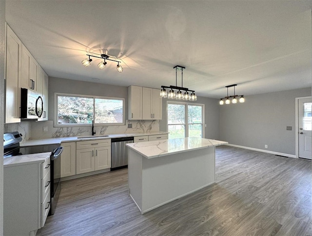 kitchen with sink, appliances with stainless steel finishes, a wealth of natural light, and white cabinetry