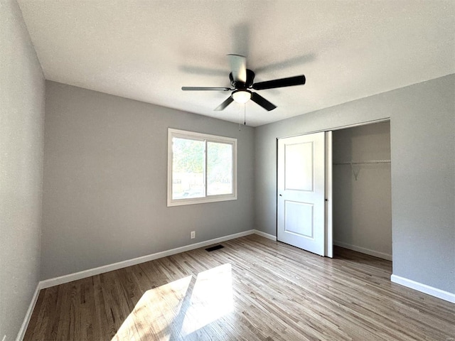 unfurnished bedroom featuring light hardwood / wood-style flooring, a closet, and ceiling fan