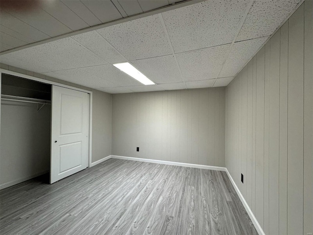 unfurnished bedroom with a paneled ceiling, a closet, and hardwood / wood-style floors