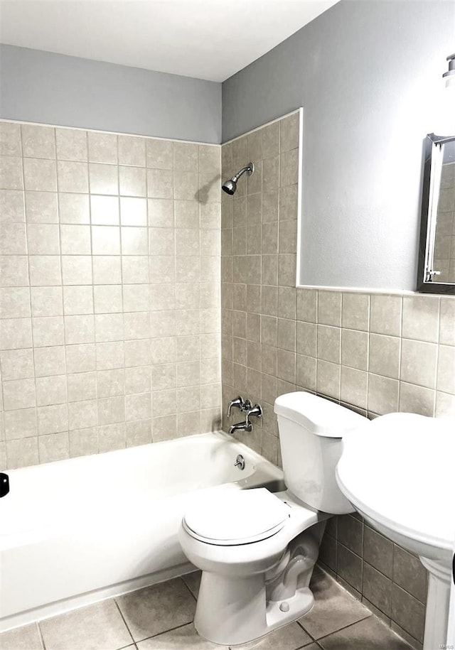 bathroom with tiled shower / bath, tile walls, toilet, and tile patterned flooring