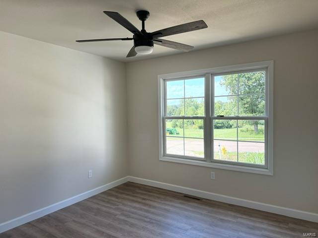 empty room with a ceiling fan, baseboards, and wood finished floors