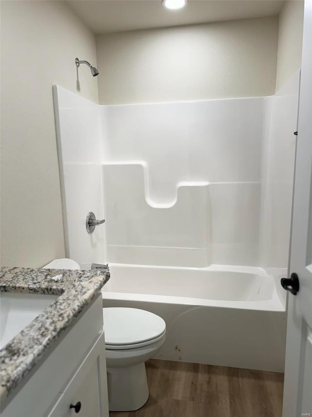 bathroom with toilet, bathing tub / shower combination, wood finished floors, and vanity