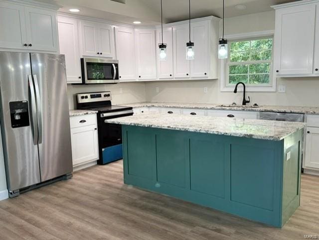 kitchen featuring appliances with stainless steel finishes, white cabinetry, light wood-type flooring, and a center island