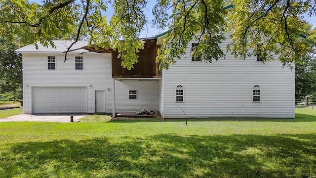 rear view of house featuring a garage and a lawn