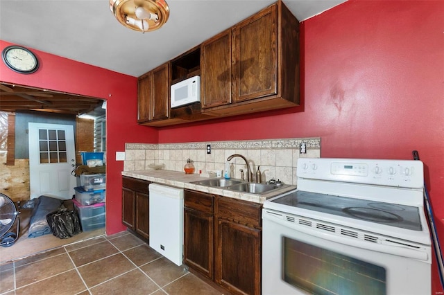 kitchen featuring sink, dark tile patterned flooring, white appliances, and backsplash