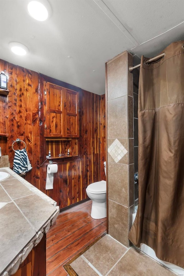 bathroom featuring wood walls, toilet, and vanity