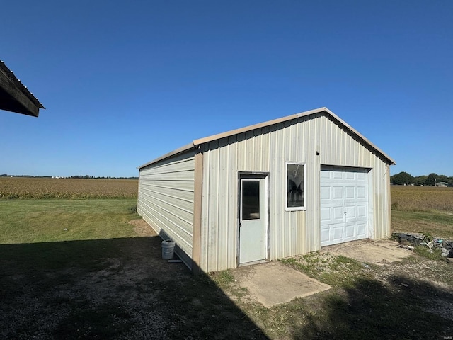 garage with a rural view and a lawn