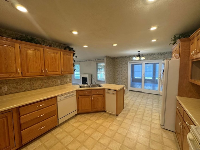 kitchen featuring white appliances, sink, kitchen peninsula, and plenty of natural light