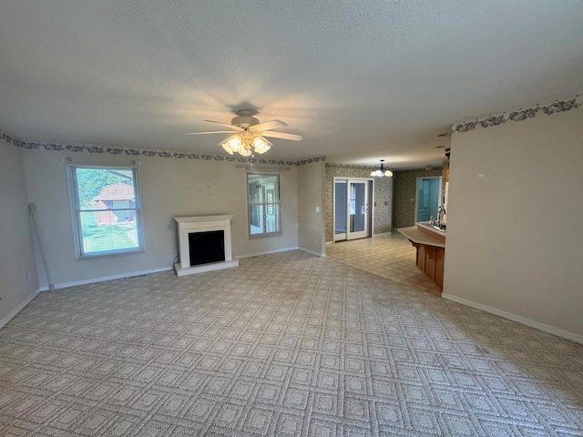 unfurnished living room featuring ceiling fan and a textured ceiling