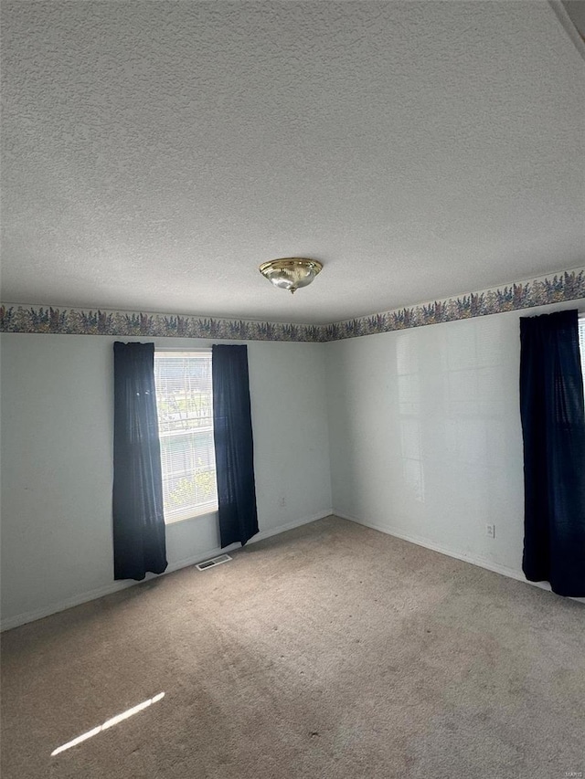 carpeted spare room with a textured ceiling