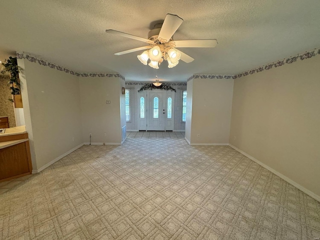 carpeted empty room featuring ceiling fan and a textured ceiling