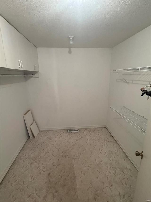 washroom with cabinets, a textured ceiling, and light carpet