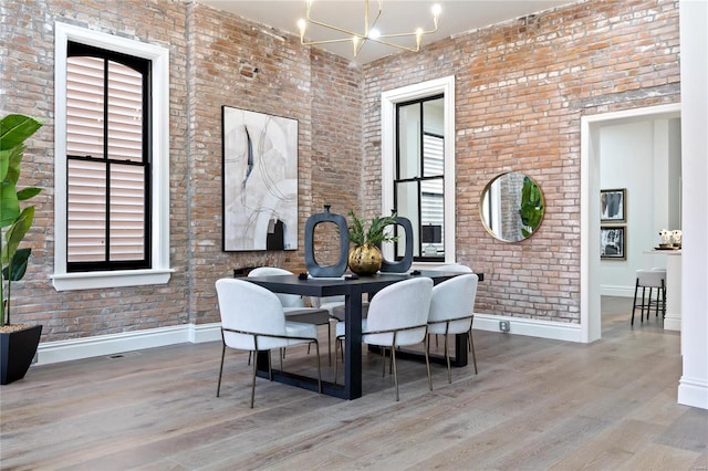 dining room featuring brick wall, light wood-type flooring, and plenty of natural light