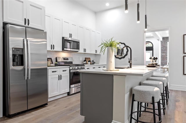 kitchen with appliances with stainless steel finishes, a breakfast bar, white cabinets, and an island with sink