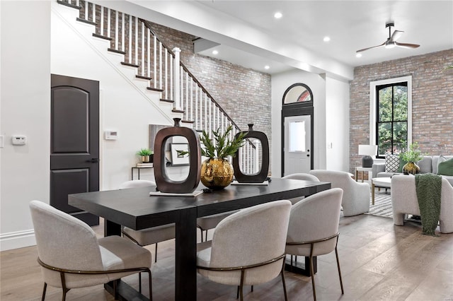 dining room featuring brick wall, light hardwood / wood-style floors, and ceiling fan