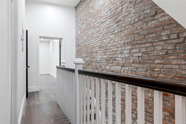 hall with brick wall and wood-type flooring