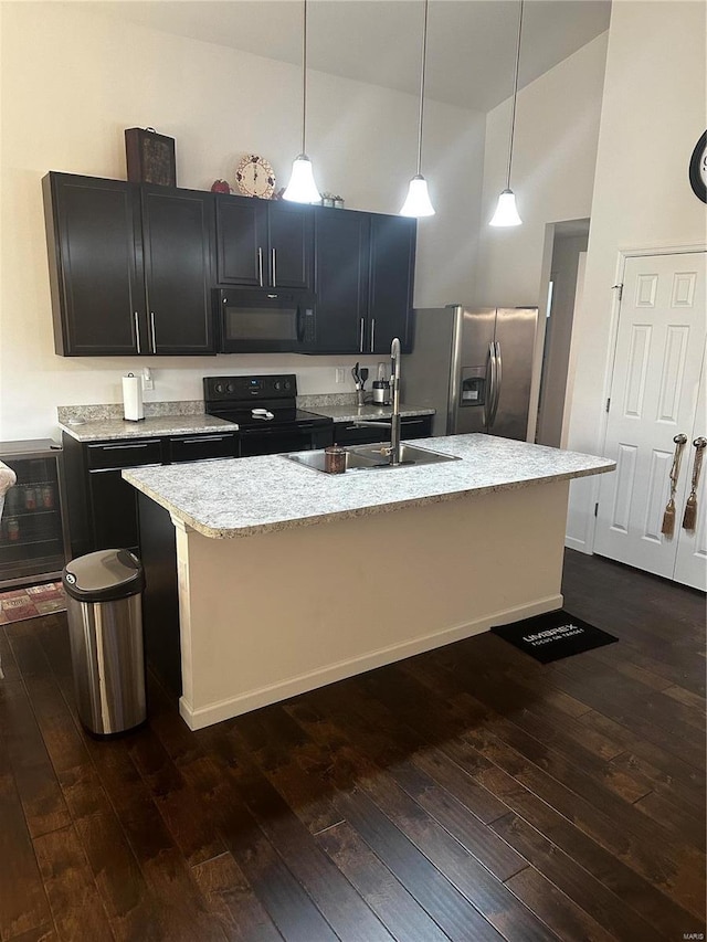 kitchen with dark wood-type flooring, black appliances, pendant lighting, high vaulted ceiling, and an island with sink