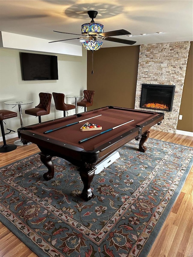 rec room with ceiling fan, a fireplace, wood-type flooring, and billiards