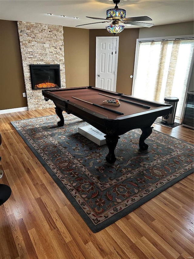 recreation room featuring hardwood / wood-style flooring, ceiling fan, a stone fireplace, and billiards