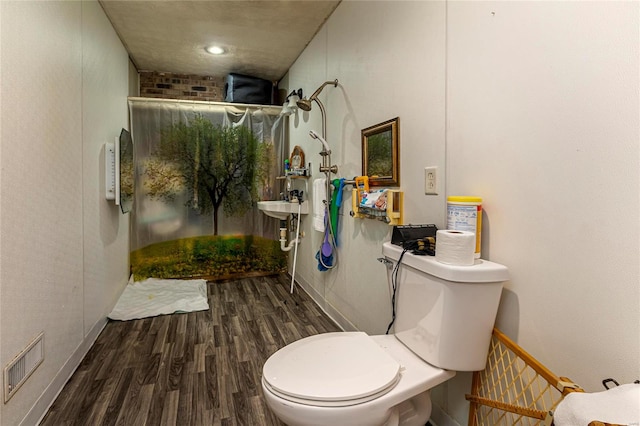 bathroom with hardwood / wood-style flooring, a shower, and toilet