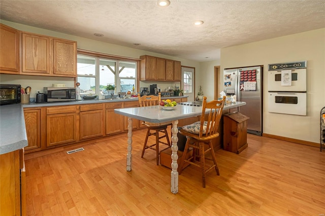 kitchen featuring a textured ceiling, appliances with stainless steel finishes, and light wood-type flooring