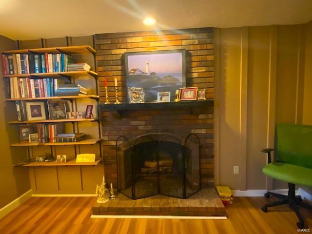 living room featuring a brick fireplace, brick wall, and hardwood / wood-style floors