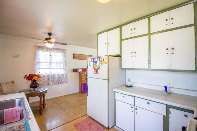 kitchen with sink, white refrigerator, white cabinetry, light hardwood / wood-style flooring, and ceiling fan