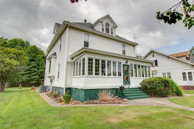 view of front of home with central AC, a sunroom, and a front yard